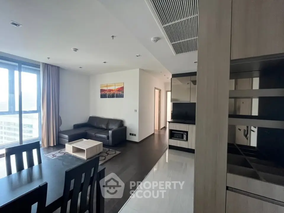Modern living room with sleek furniture and large windows offering city views.