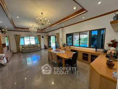 Spacious living room with elegant chandeliers and large windows offering garden views.