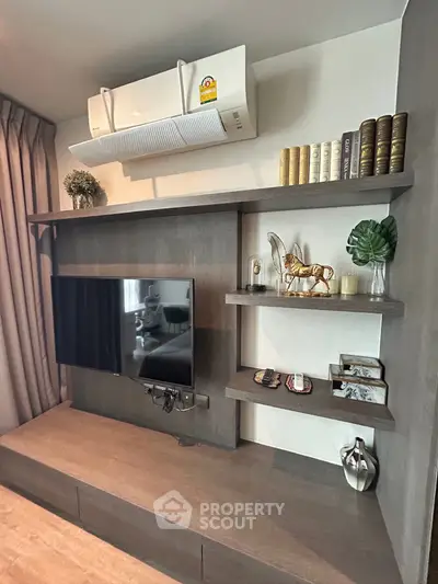 Modern living room with stylish shelving and mounted TV, featuring elegant decor and air conditioning unit.