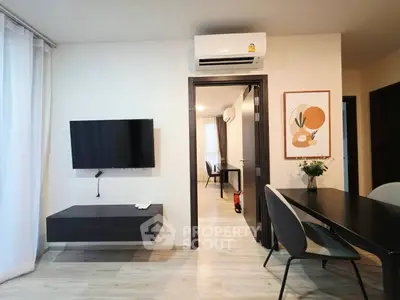 Modern living room with wall-mounted TV and sleek dining area in stylish apartment.