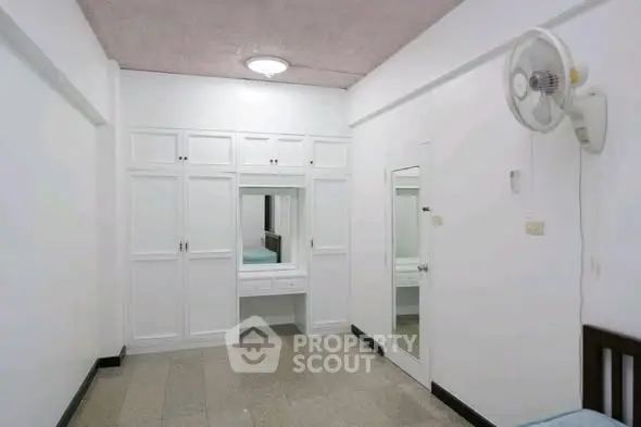 Spacious bedroom with built-in wardrobe and wall-mounted fan, ideal for comfortable living.