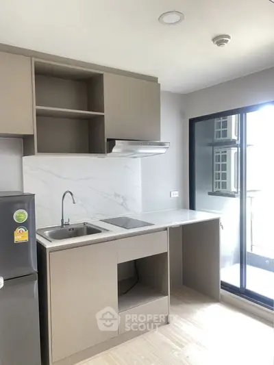 Modern kitchen with sleek cabinetry and balcony access in a stylish apartment.