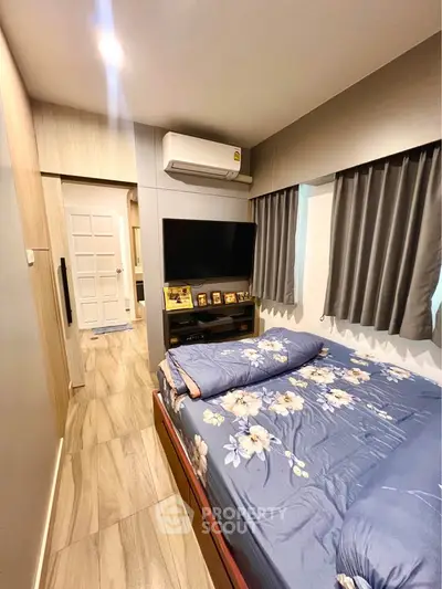 Cozy bedroom with modern decor, featuring a wall-mounted TV and air conditioning, perfect for relaxation.