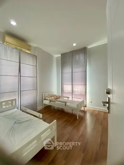 Spacious bedroom with wooden flooring and natural light