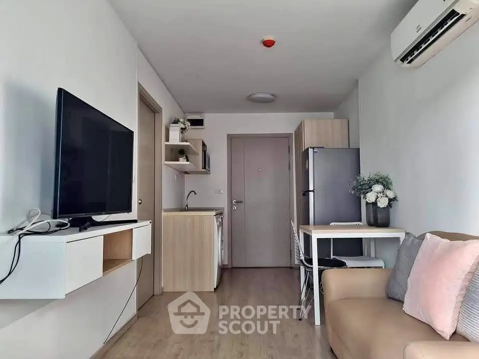 Modern compact living room with kitchen, featuring sleek furniture and neutral tones for a cozy ambiance.