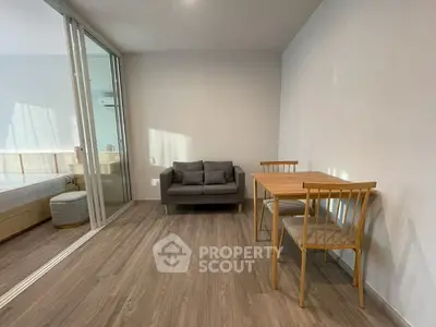 Modern studio apartment with sleek wooden flooring and cozy furniture, featuring a compact dining area and a comfortable sofa.