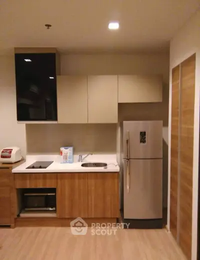Modern kitchen with sleek cabinets and stainless steel fridge in cozy apartment