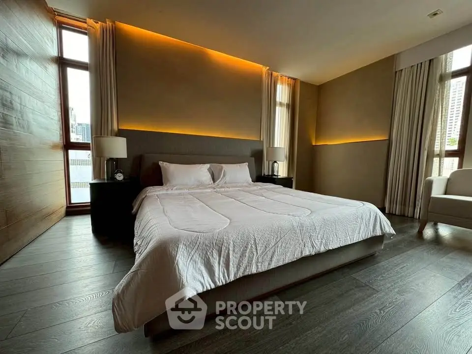 Luxurious bedroom with modern lighting and large windows in upscale apartment.