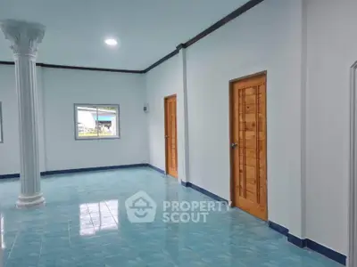 Spacious interior with blue tiled floor and wooden doors, featuring a decorative column.