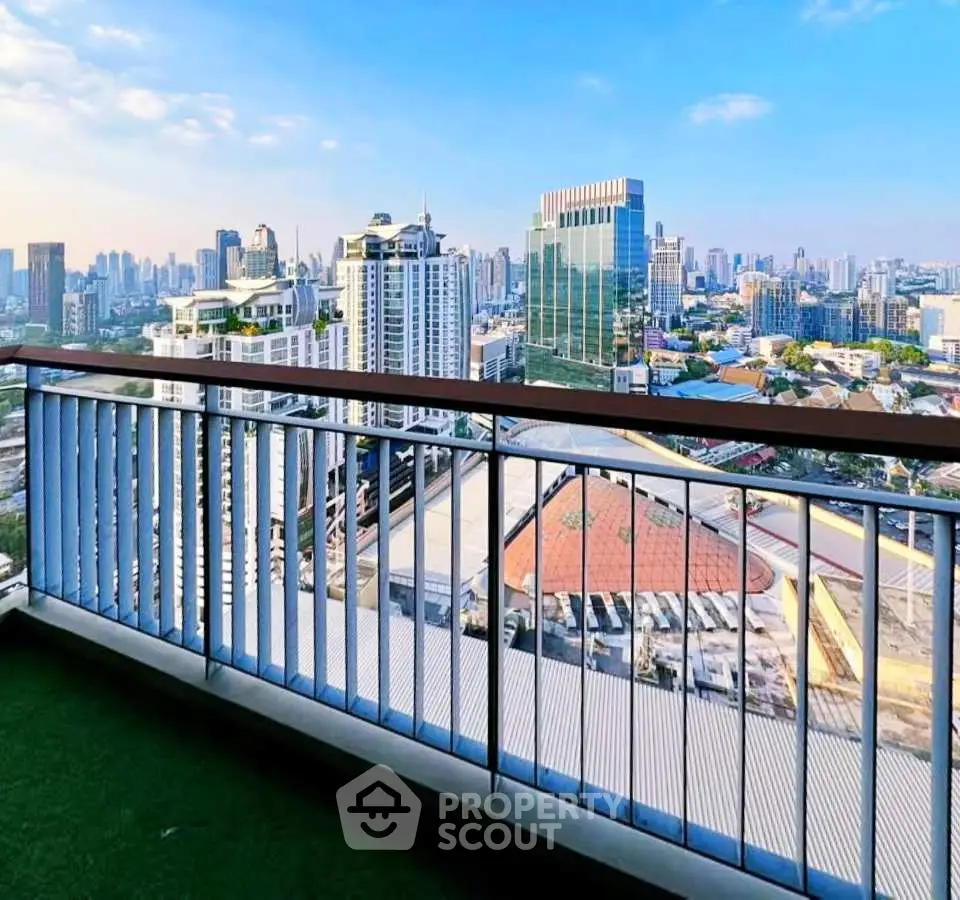 Stunning cityscape view from a high-rise balcony with modern railing and lush green flooring.