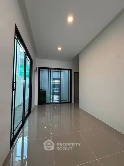 Spacious modern living room with sleek tile flooring and large glass doors for natural light.