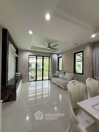 Spacious modern living room with elegant decor and large windows offering garden views.