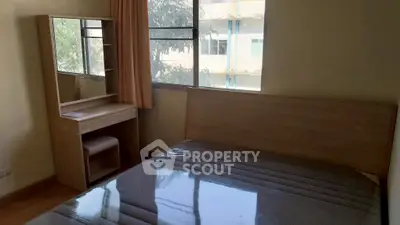 Cozy bedroom with large window and wooden furniture, perfect for natural light lovers.