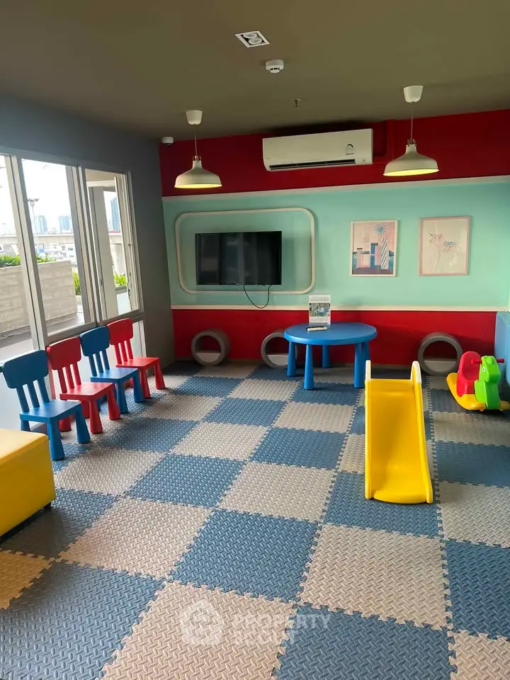 Vibrant children's playroom with colorful chairs, slide, and city view.