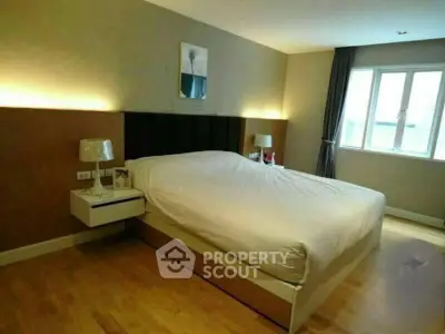 Spacious modern bedroom with elegant lighting and large window for natural light.