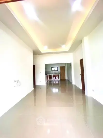 Spacious open-plan living area with modern kitchen and glossy tiled floors.