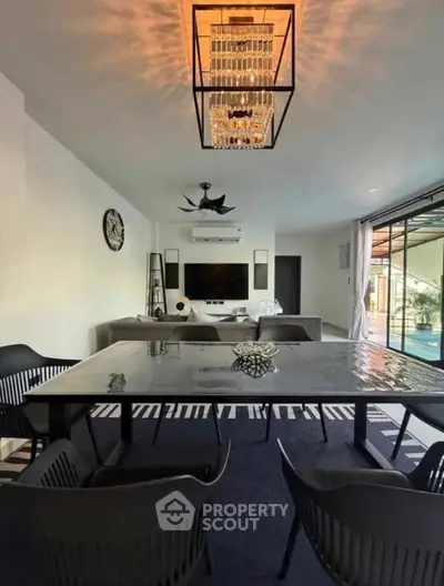 Modern living room with elegant chandelier and stylish furniture, featuring a spacious open layout and large windows.