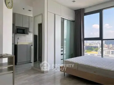 Modern studio apartment with city view, featuring sleek kitchen and cozy bedroom area.