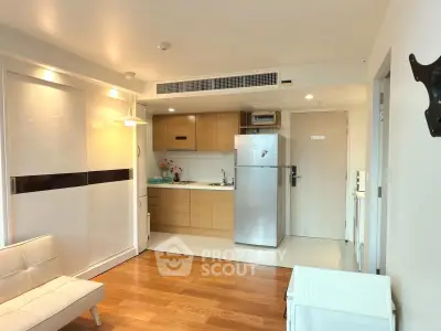 Modern studio apartment with sleek kitchen and cozy living area, featuring wooden flooring and contemporary design.
