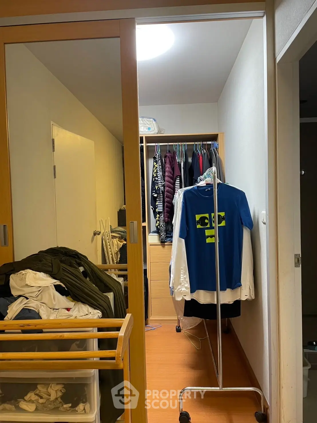 Spacious walk-in closet with ample storage and hanging space, featuring wooden flooring and sliding doors.