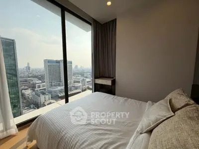 Luxurious bedroom with stunning city view from floor-to-ceiling windows in high-rise apartment.