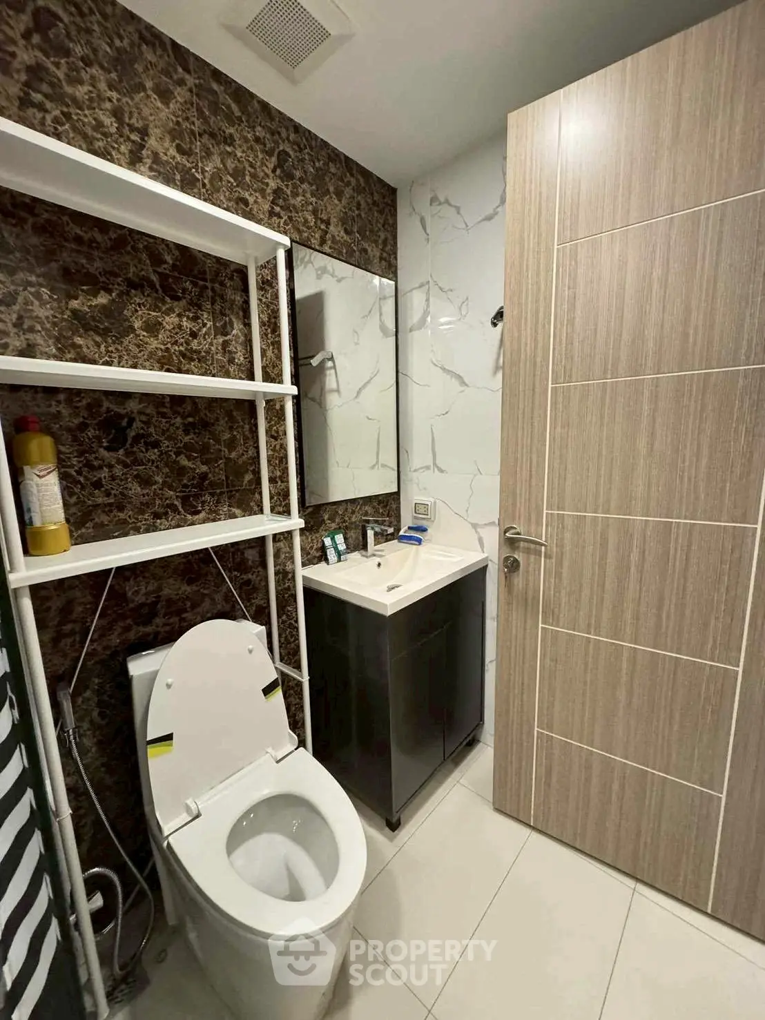 Modern bathroom with sleek design, featuring a toilet, sink, and stylish wall tiles.