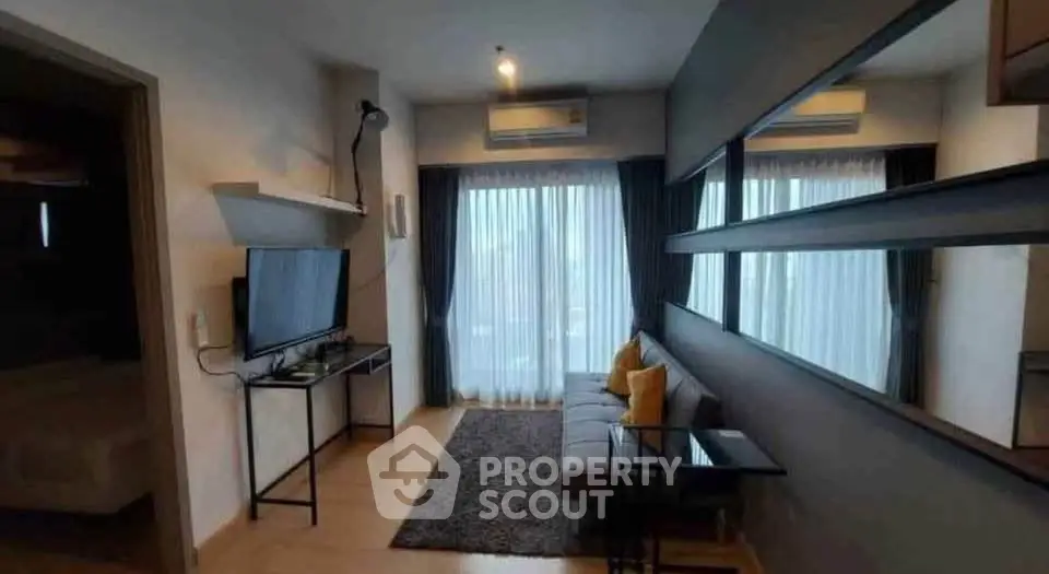 Modern living room with sleek design, featuring a cozy sofa, wall-mounted TV, and large windows for natural light.