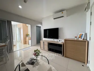 Modern living room with sleek furniture and large TV, open layout to bedroom, bright and inviting space.