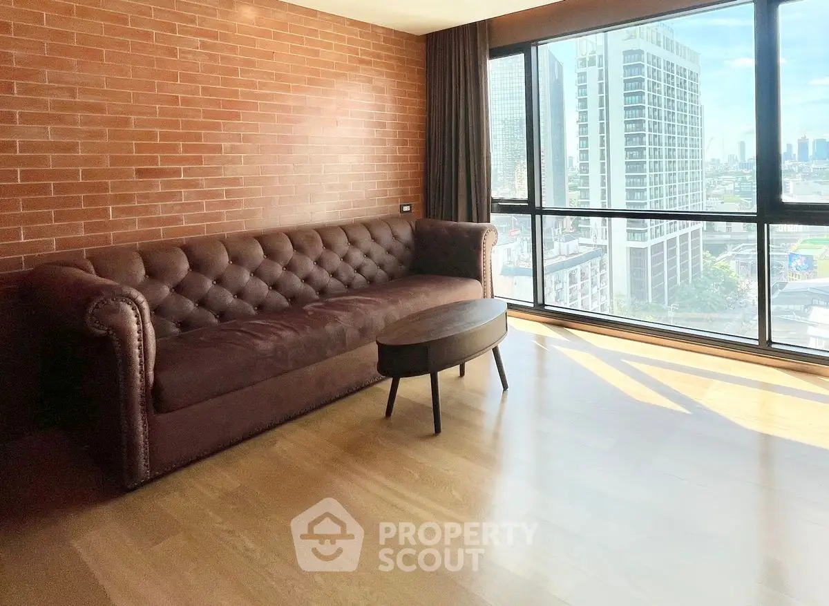 Spacious living room with brick wall and city view, featuring a brown sofa and modern coffee table.
