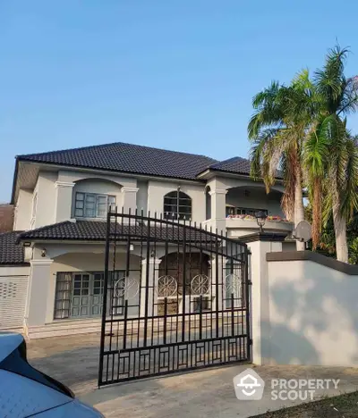 Stunning two-story house with gated entrance and palm trees, perfect for luxurious living.