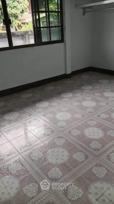 Spacious empty room with tiled flooring and large windows, perfect for customization.