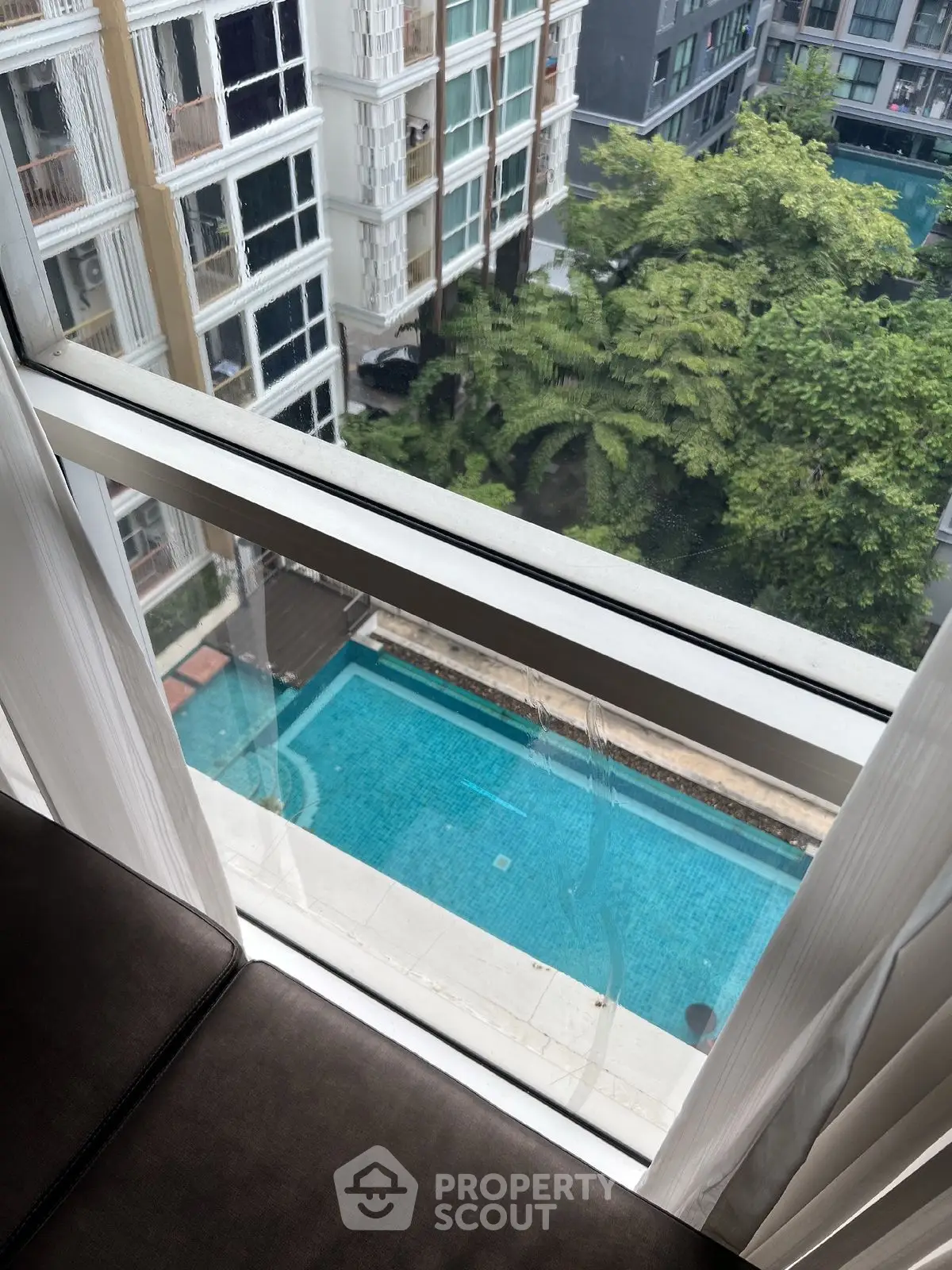 Stunning high-rise view of pool and greenery from apartment window