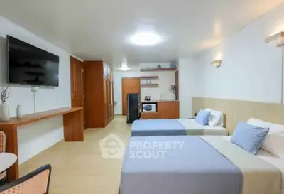 Spacious modern bedroom with twin beds and kitchenette, ideal for comfortable living.
