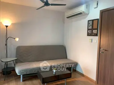 Cozy living room with modern sofa, air conditioning, and stylish lighting in a compact apartment.