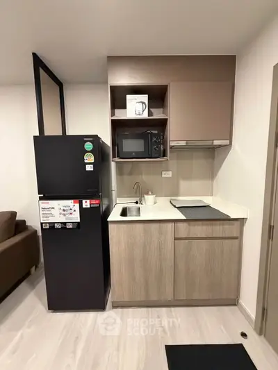 Modern compact kitchen with sleek appliances and stylish cabinetry in a cozy apartment setting.