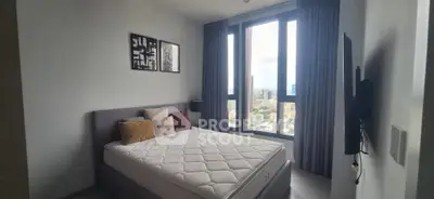 Modern bedroom with large windows offering stunning city views, featuring a comfortable bed and stylish decor.