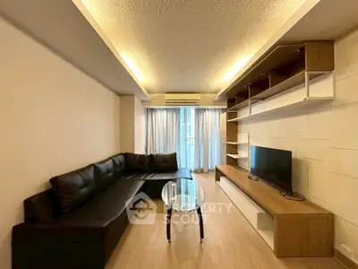 Modern living room with sleek black sofa, stylish shelving, and a large window for natural light.