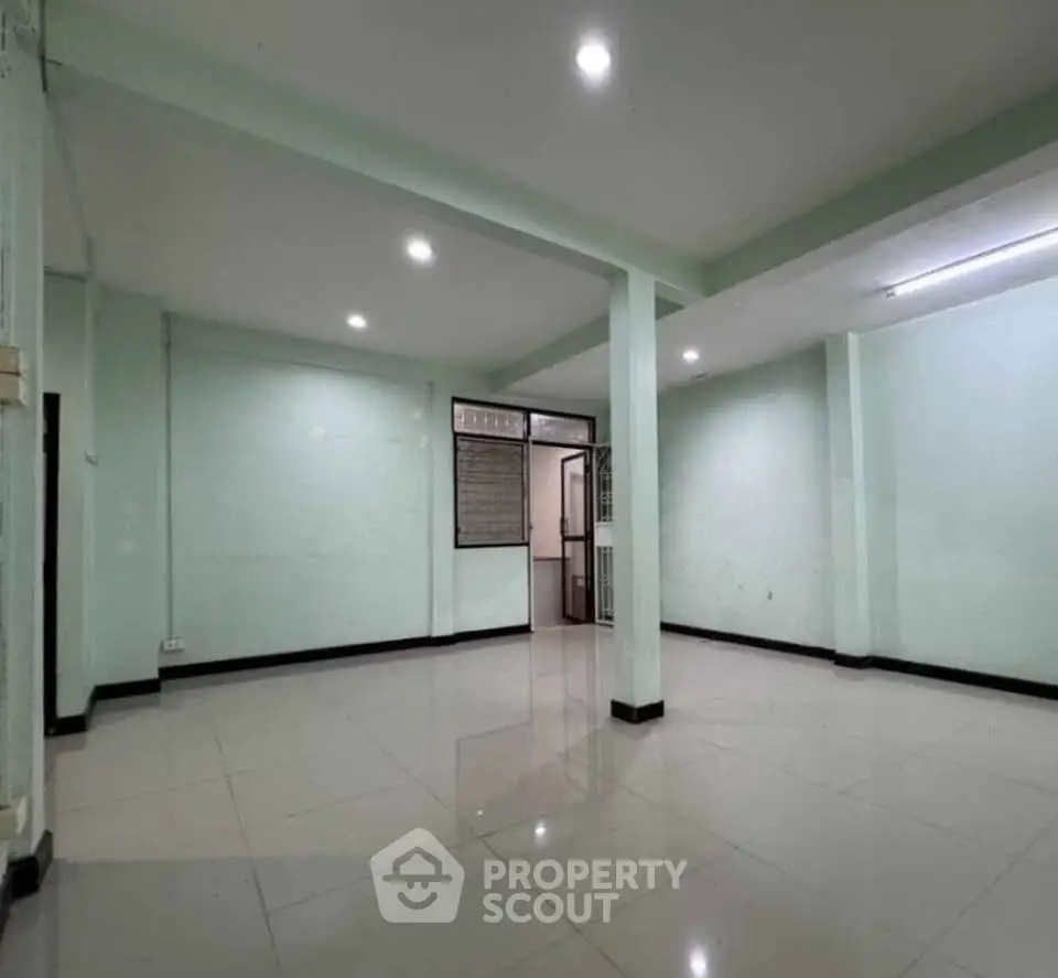 Spacious open-plan room with tiled flooring and modern lighting, ideal for versatile living or office space.