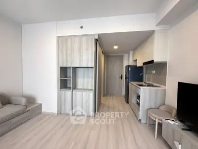 Modern open-plan living room with sleek kitchen and cozy seating area, perfect for urban living.