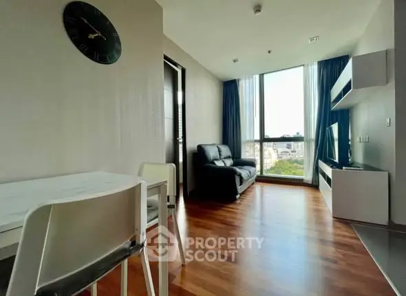 Modern living room with wooden flooring, large window, and sleek furniture.