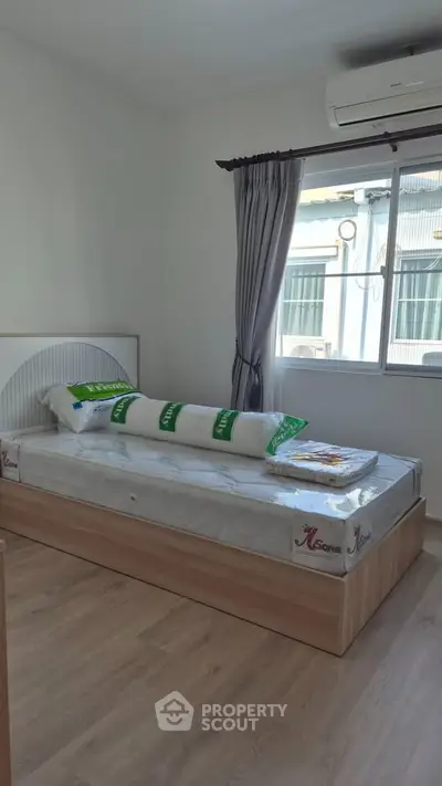 Cozy bedroom with single bed, air conditioning, and large window for natural light.