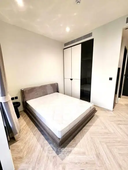 Modern bedroom with sleek design and ample natural light, featuring a comfortable bed and stylish flooring.