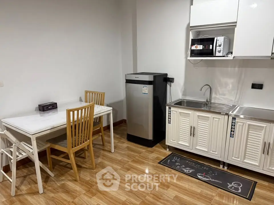 Modern kitchen with sleek appliances and dining area in a cozy apartment.