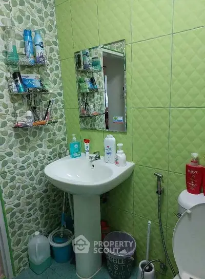 Charming bathroom with green tiles and modern fixtures, perfect for a cozy home.