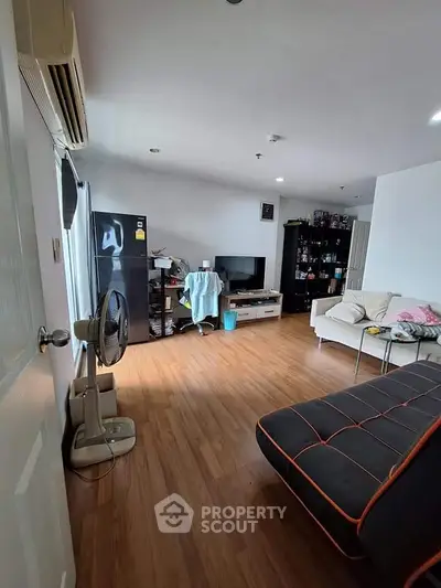 Spacious living room with modern decor and wooden flooring, featuring a cozy sofa and entertainment setup.