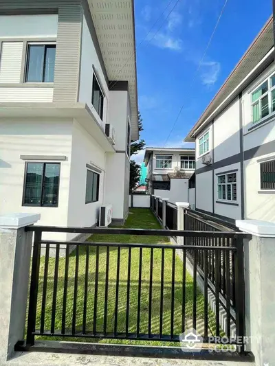 Modern residential building exterior with lush green lawn and clear blue sky