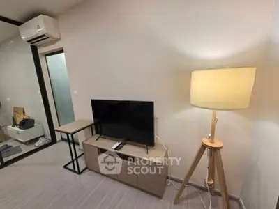 Modern living room with sleek TV stand, stylish lamp, and air conditioning unit.