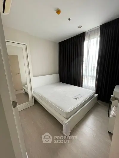 Modern bedroom with large window and minimalist decor in a stylish apartment.