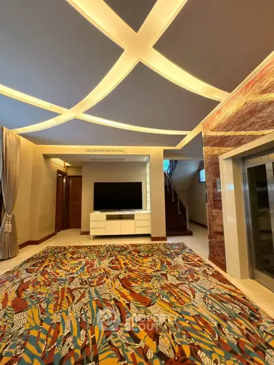 Luxurious living room with modern ceiling design and vibrant carpet, featuring a sleek TV setup and elegant decor.
