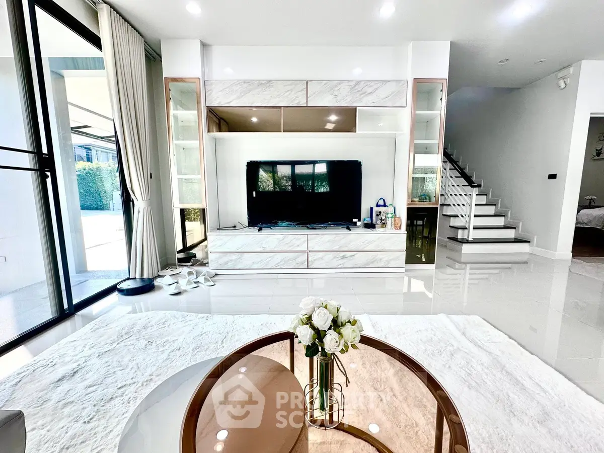 Luxurious modern living room with sleek design and elegant decor, featuring a large TV and stylish furniture.